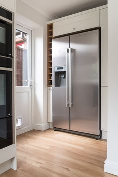 a stainless steel refrigerator freezer sitting inside of a kitchen next to a wooden floor