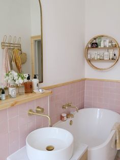 a bath tub sitting under a bathroom mirror next to a white sink in a bathroom