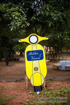 a yellow scooter sign sitting on the side of a road next to trees