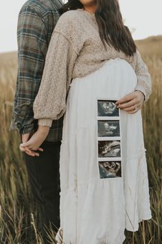 a pregnant couple standing in tall grass holding each other