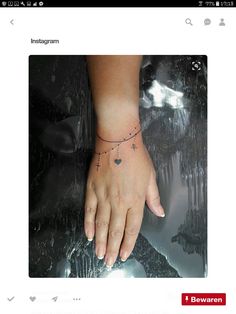 a woman's hand with a cross and heart tattoo on her left side wrist