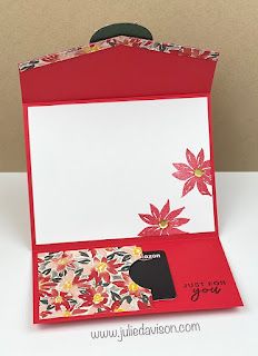 an open red box with flowers inside on a white tableclothed surface and the lid opened to reveal a card