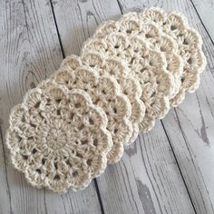 three crocheted coasters sitting on top of a wooden floor