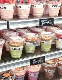 there are many cups of ice cream on the shelf in the store and one is filled with berries