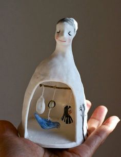 a hand holding a small white figurine with a bird in it