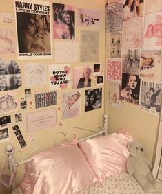 a bed with pink sheets and pictures on the wall above it, along with a teddy bear