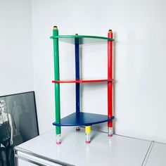 a multicolored shelf sitting on top of a white dresser next to a black and white photo