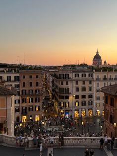 people are walking around in the city at sunset or dawn, with buildings and lights on either side