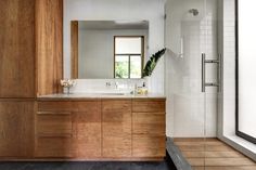 a large bathroom with wooden cabinets and white tile on the walls, along with a walk in shower