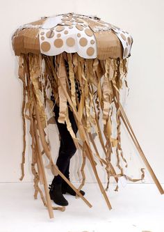 a woman is standing under an umbrella made out of sticks and cardboard strips with polka dots on it