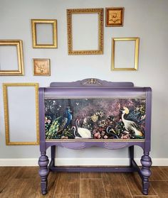 a purple dresser with paintings on the wall