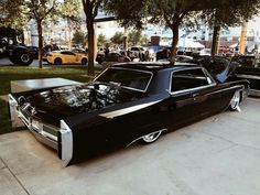 an old black car is parked on the sidewalk