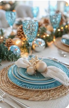 the table is set with blue and white plates, silverware and pineconis