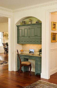 a kitchen with wooden floors and green cabinets in the corner, along with an area rug on the hard wood flooring