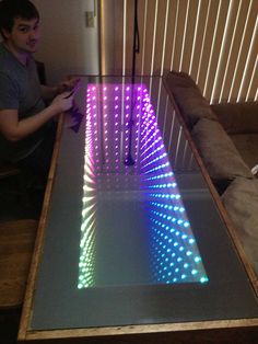 a man sitting in front of a table that has lights on it and is looking at his cell phone