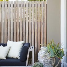 a blue couch sitting on top of a wooden deck next to a planter filled with succulents