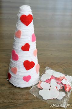 a small white cone with hearts on it next to a bag of confetti