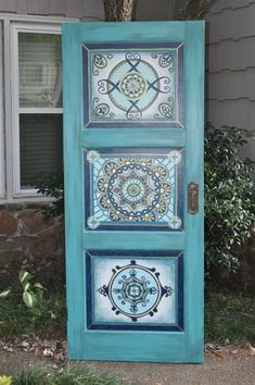 an old door painted with blue and white tiles on the outside, in front of a house