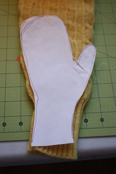 a pair of oven mitts sitting on top of a cutting board next to a ruler