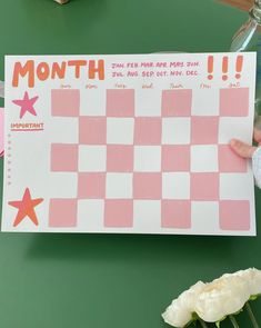 a person holding up a pink and white checkered paper with the words month on it