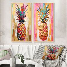 two colorful pineapples are hanging on the wall above a white couch in a living room