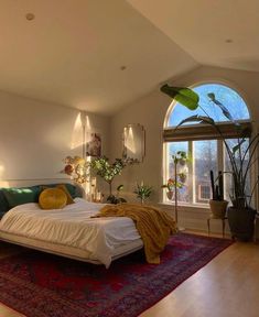 a bedroom with a large bed and lots of plants in the window sill area