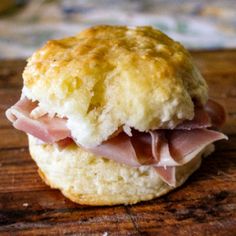 a ham and cheese biscuit sitting on top of a wooden cutting board with the words national cold cuts day