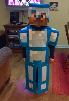 a young boy dressed up as a minecraft character in front of a flat screen tv