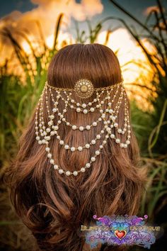 the back of a woman's head with pearls and chains on it