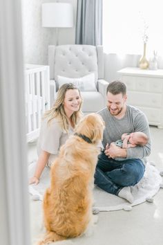 a man and woman are sitting on the floor with their baby in front of them