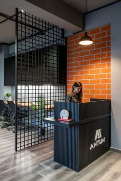 a woman standing at a podium in front of a brick wall with an atm logo on it