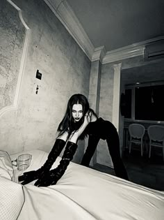 a woman sitting on top of a bed in black and white