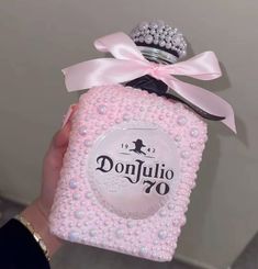 a person holding a pink bottle with pearls on it