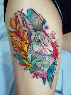 a rabbit tattoo on the thigh with colorful flowers