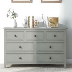 a white dresser with two framed pictures on it