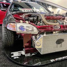 the front end of a red sports car with its hood up and engine in view