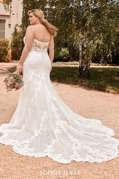 a woman in a white wedding dress standing on gravel with her back to the camera