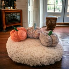 three crocheted pumpkins sitting on top of a round rug in a living room