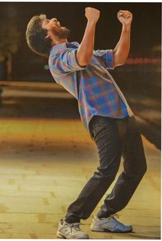 a man with his arms in the air while standing on a skateboard at an indoor skating rink