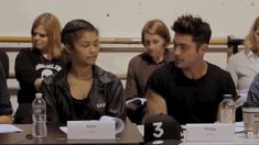 two people sitting next to each other in front of a table with water bottles on it