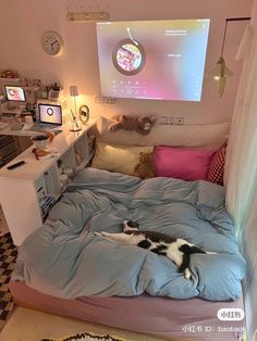 a cat laying on top of a bed in front of a projector screen above it