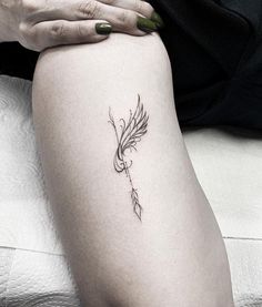 a woman's leg with a feather tattoo on her left thigh and the word love written in cursive writing