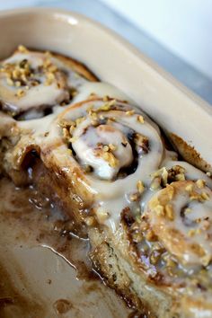 cinnamon rolls with icing and nuts in a baking dish, ready to be eaten