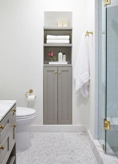 a white bathroom with gray cabinets and toilet