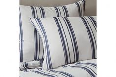 two white and blue striped pillows on a bed