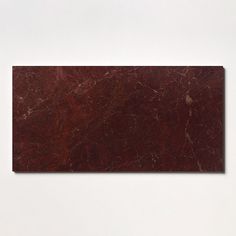 a piece of red marble sitting on top of a white wall