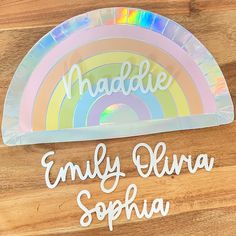 personalized name plate on wooden surface with rainbow design and handwritten name in white letters