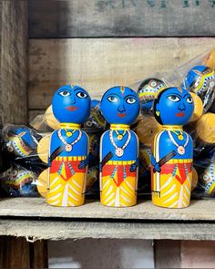 a group of blue and yellow dolls sitting next to each other on a wooden shelf