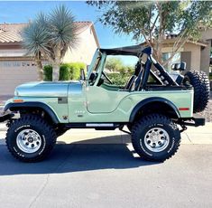 a light green jeep parked in front of a house