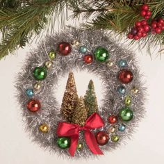 an ornament hanging from a christmas tree with ornaments around it and a red bow